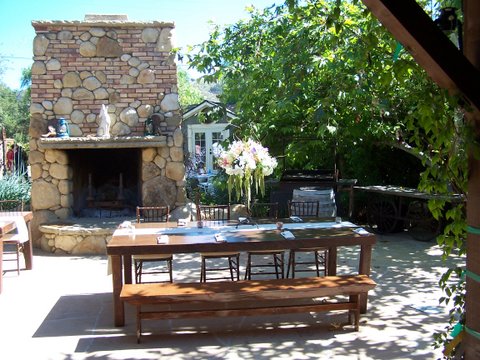 table and bench seat setup next to fireplace outside at a winery