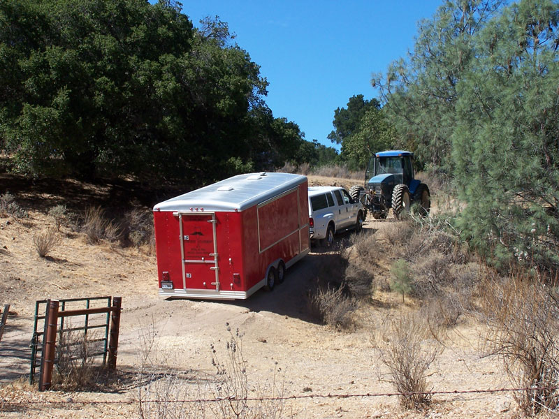 tractor and SUV towing big red up a hill