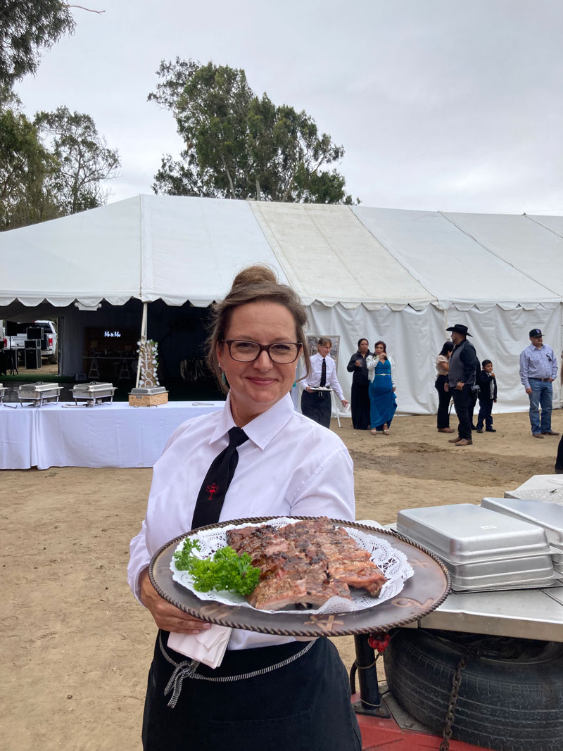 Smiling server holding platter of BBQ'd ribs