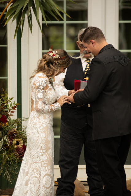 groom sliding ring on brides hand while Billy officiates