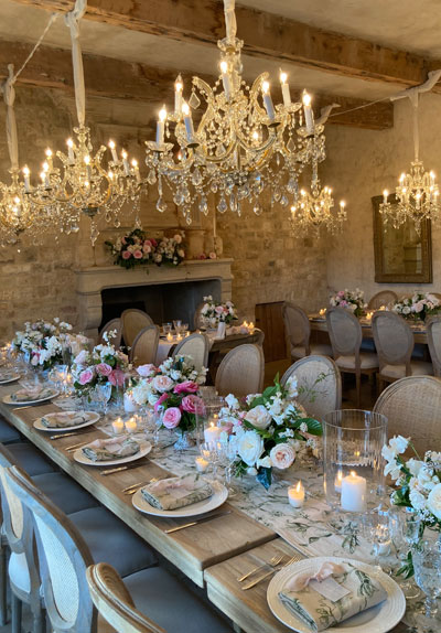 Room decorated for wedding dinner with chandeliers and elegant table settings.
