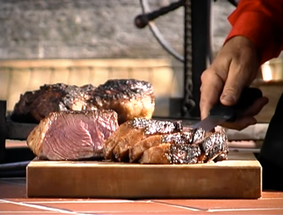 still from video of a hand holding a knife while cutting beef