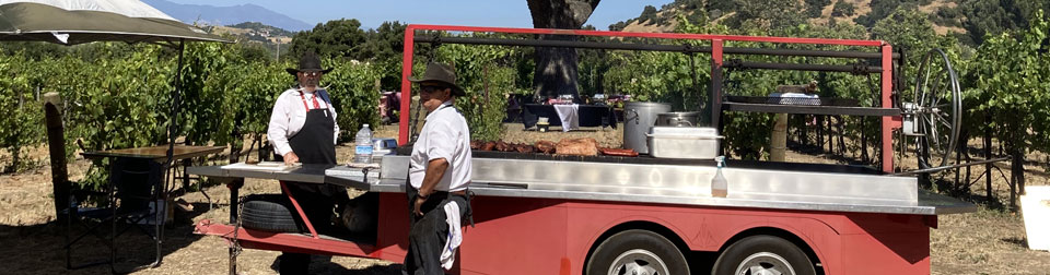 Billy and another cook standing in vineyard next to grill